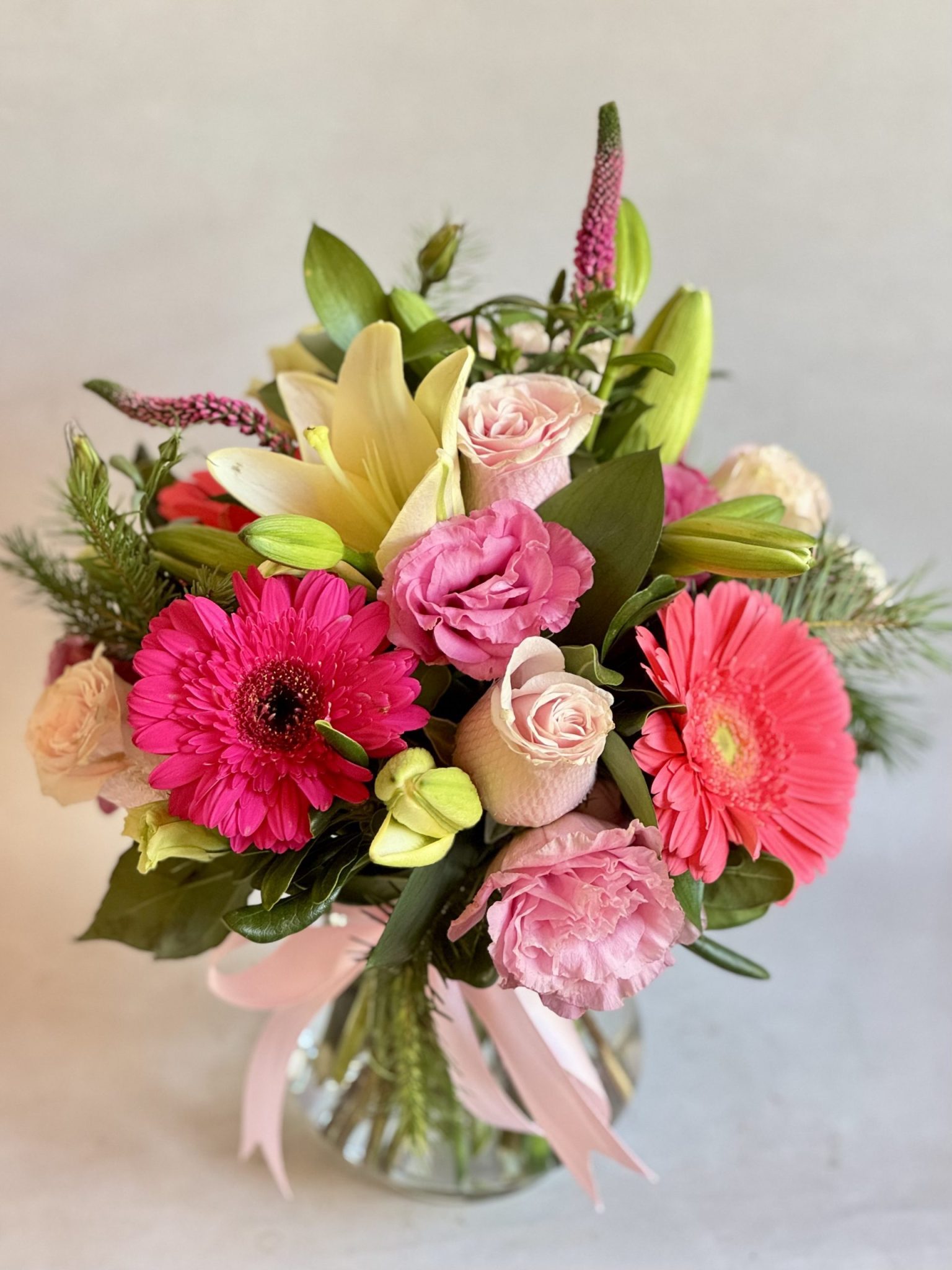 Florero de vidrio con rosas y gerberas